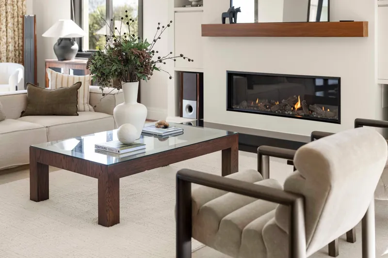Lounge detail with gas fireplace, glass coffee table and armchair