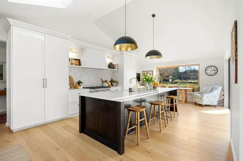 Kitchen with dark timber island, brass pendant lights and garden views
