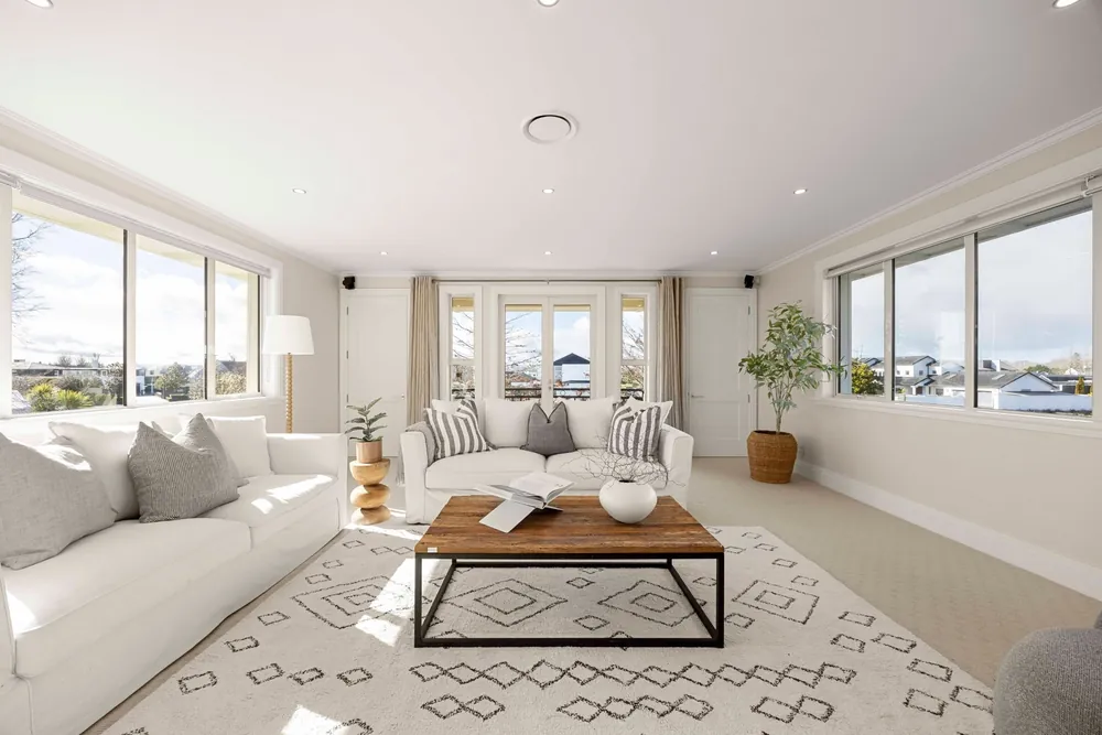 Bright living room with white sofas, timber coffee table and views over the neighbourhood
