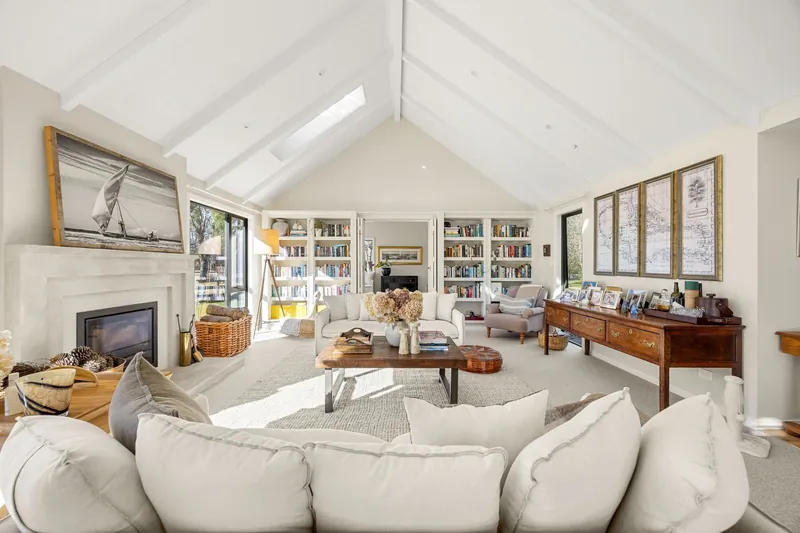 Vaulted living room with exposed beams, fireplace and built-in bookshelves