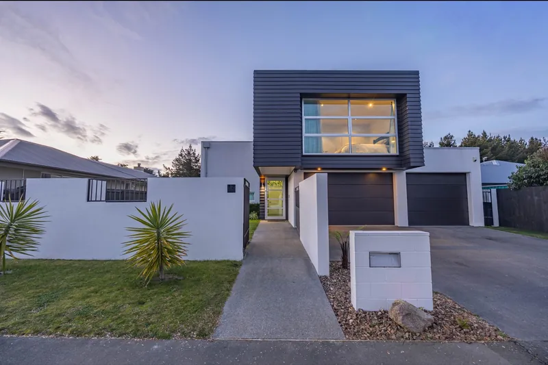 Modern two-storey home at dusk with a lit upstairs window